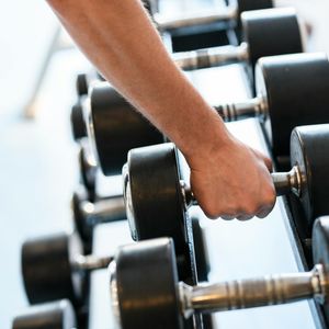 Close-up of hands gripping a dumbbell, showing texture and effort.