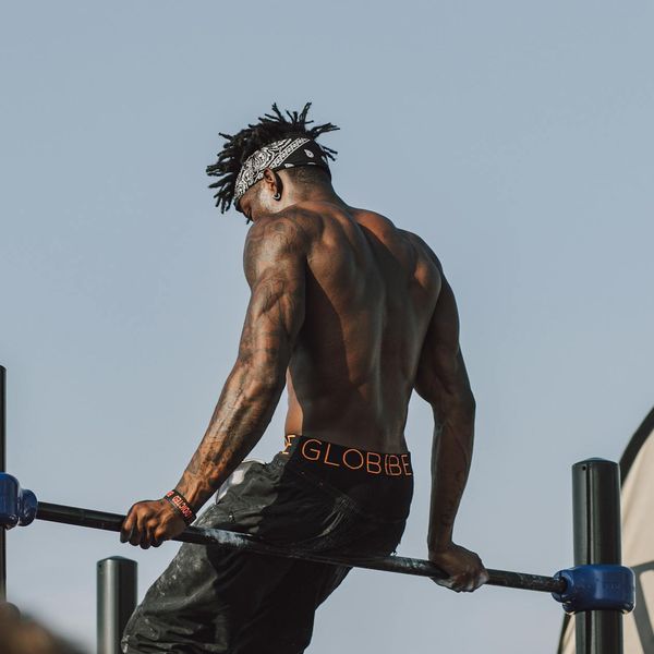 Man's muscular back as he performs a pull-up, showing concentration.
